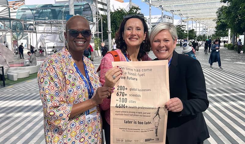 Three women holding up a newspaper regarding climate news